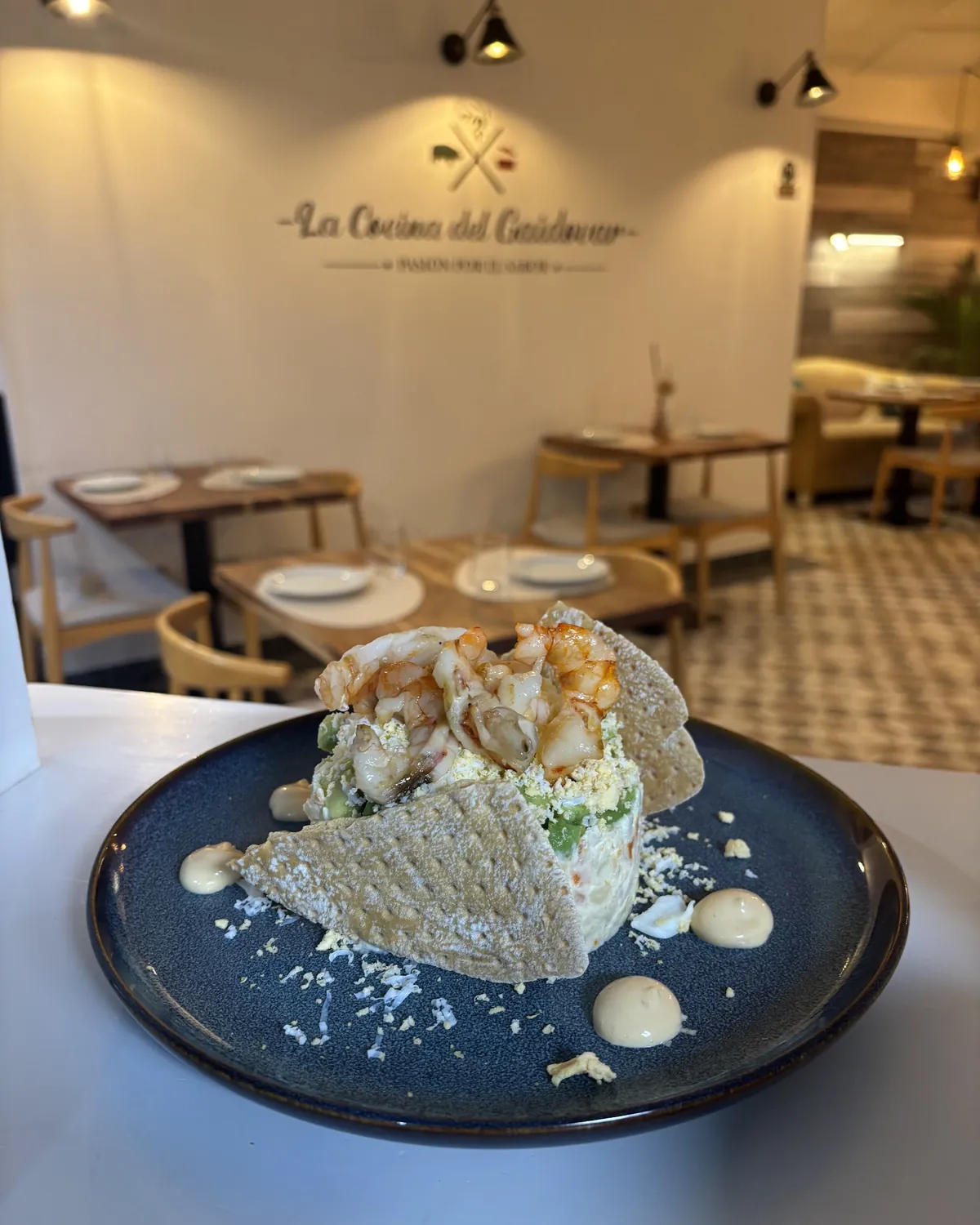 Comedor de La Cocina del Gaidovar en Grazalema, con el rótulo del restaurante en la pared y una ensaladilla en primer plano