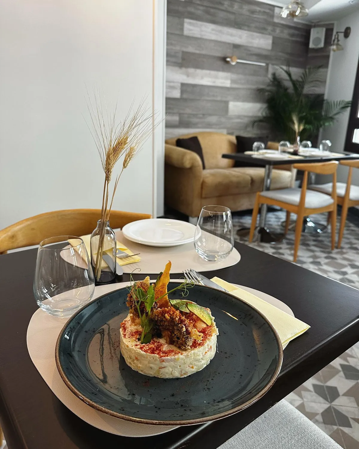 Mesa montada en el comedor de La Cocina del Gaidovar, con un plato de ensaladilla y el suelo hidráulico del salón