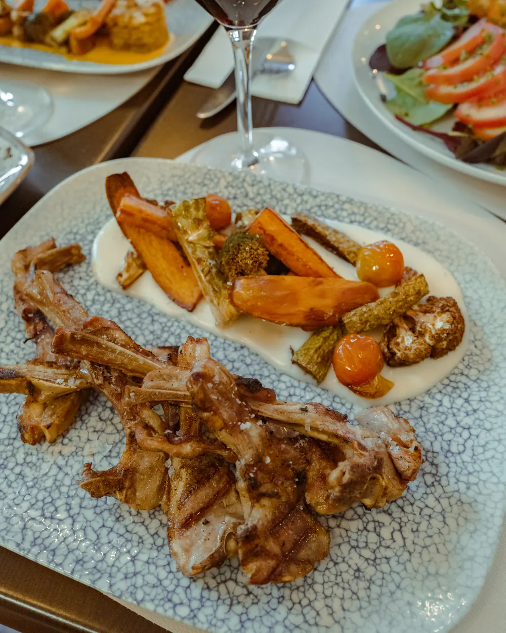 Chuletas con puré y verduras, en la mesa junto a una copa de vino tinto